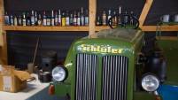 Ein alter gr&uuml;ner Schl&uuml;ter Traktor steht in der Werkstatt